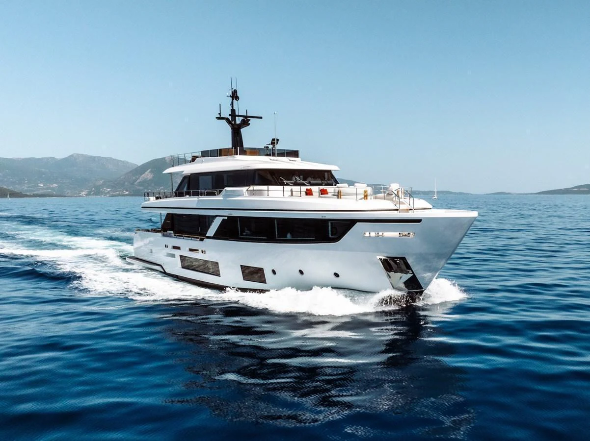 A sleek and modern yacht cruising on calm blue waters with a mountainous backdrop. aboard AT ONE Yacht for Sale