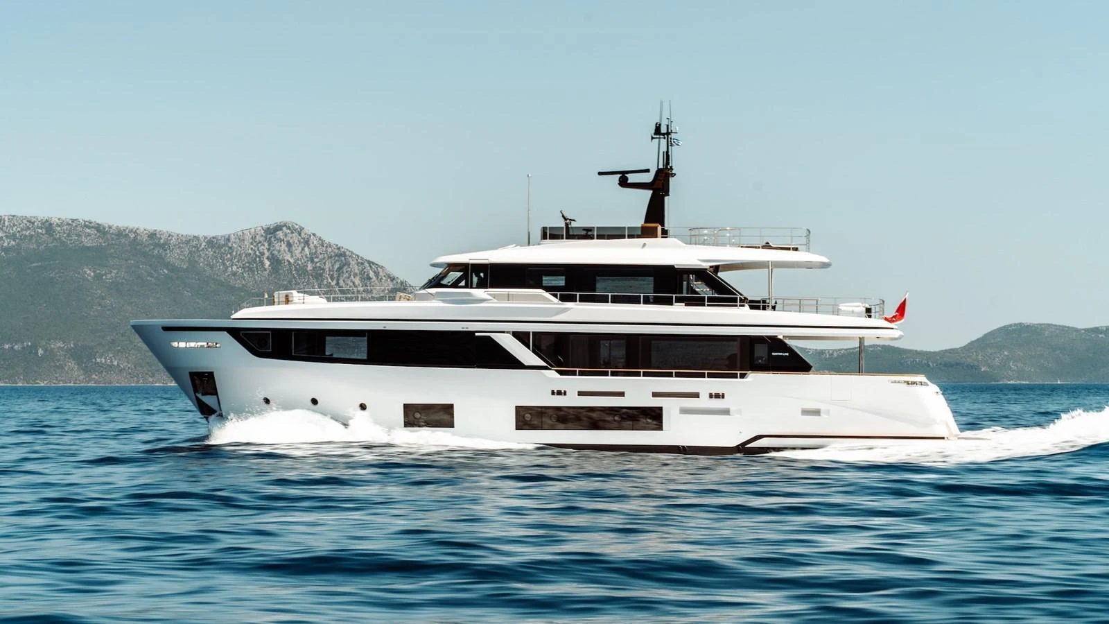 A sleek and modern yacht cruising on calm waters with a scenic mountainous backdrop. aboard AT ONE Yacht for Sale