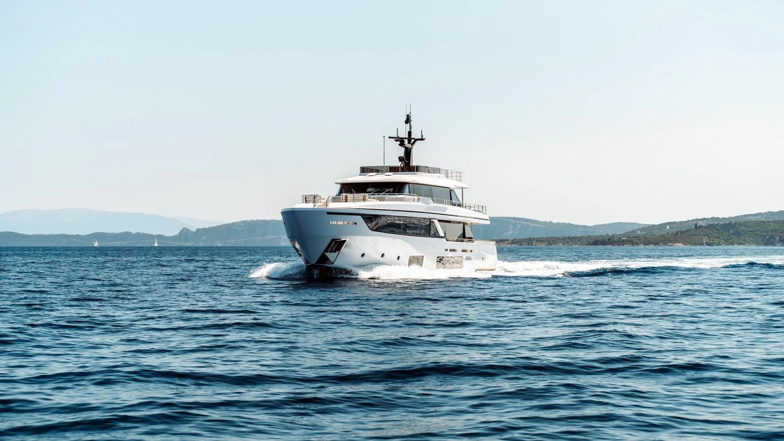 A sleek yacht cruises through calm waters with a scenic backdrop. aboard AT ONE Yacht for Sale