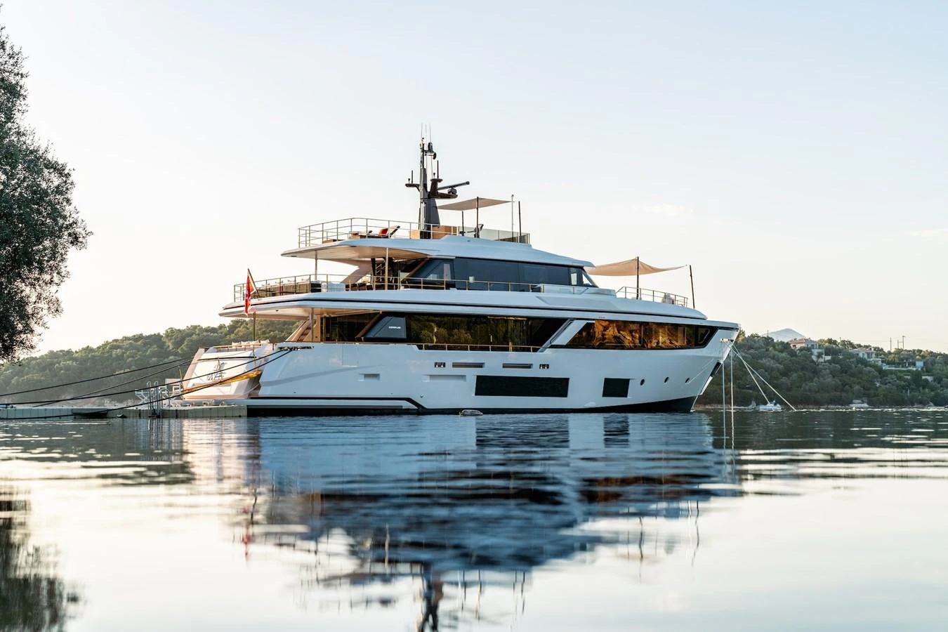 A sleek and modern yacht is anchored in calm waters, reflecting the serene surroundings. aboard AT ONE Yacht for Sale