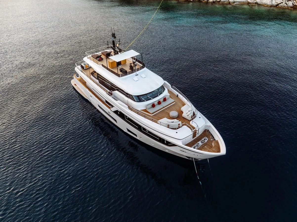 A stunning yacht is anchored in calm, clear waters, showcasing its sleek design and luxurious deck space. aboard AT ONE Yacht for Sale