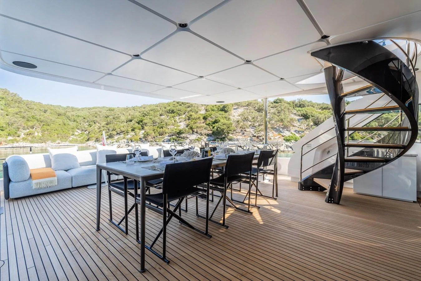 The aft deck features a stylish dining area with a spiral staircase and comfortable seating, perfect for alfresco dining. aboard AT ONE Yacht for Sale
