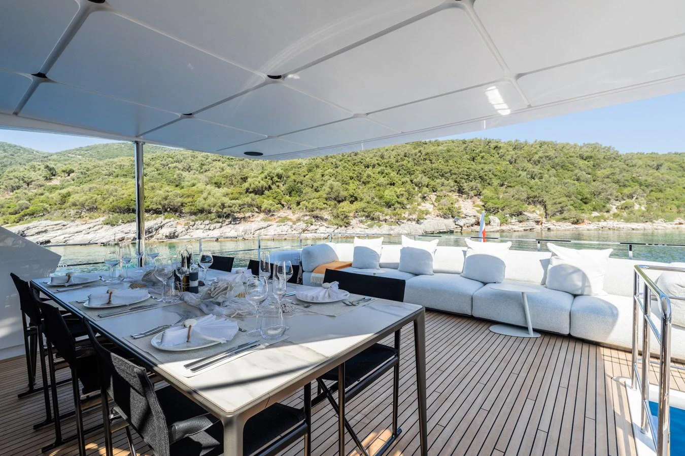 The aft deck features an elegant dining area with a scenic view of the surrounding landscape. aboard AT ONE Yacht for Sale
