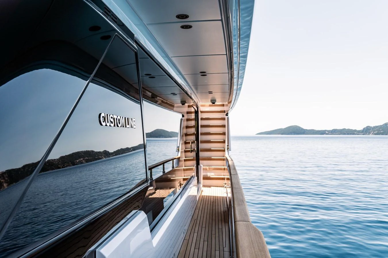 The sleek side deck of the yacht offers a serene view of the open water and distant islands. aboard AT ONE Yacht for Sale