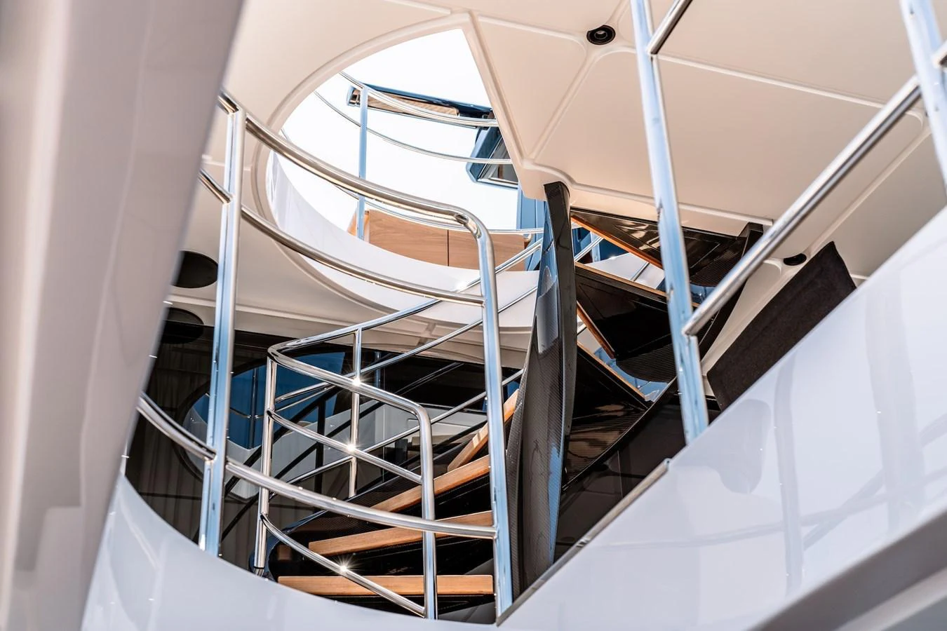 A sleek and modern staircase with polished metal railings and wooden steps connects the yacht's levels. aboard AT ONE Yacht for Sale
