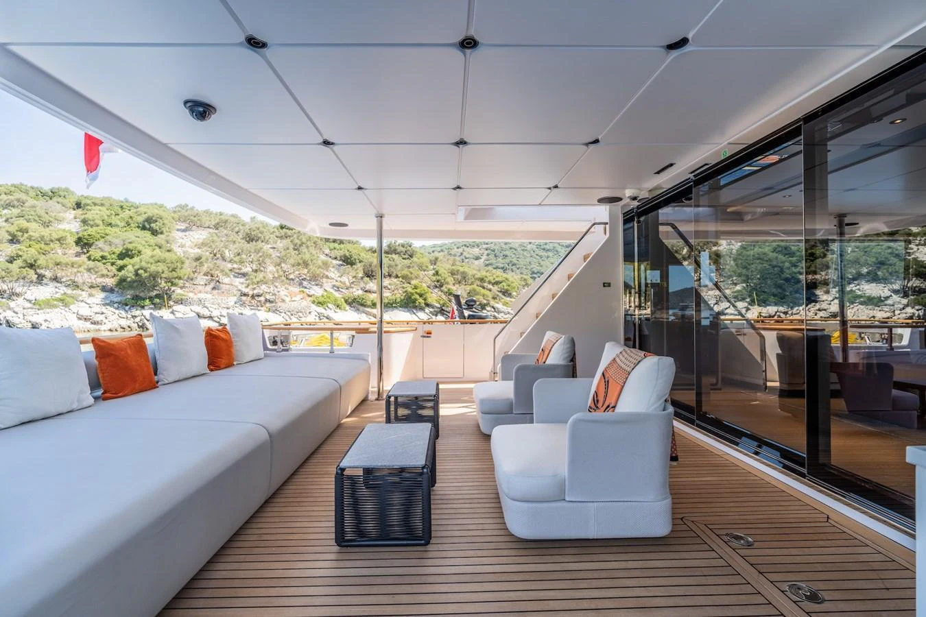 The aft deck features a spacious seating area with plush cushions and a serene view of the surrounding landscape. aboard AT ONE Yacht for Sale