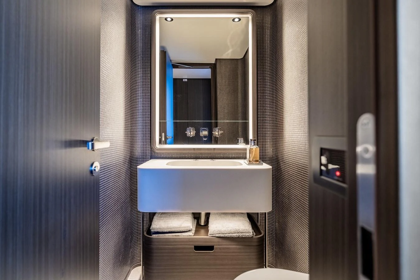A sleek and modern yacht bathroom with a well-lit vanity mirror and contemporary fixtures. aboard AT ONE Yacht for Sale