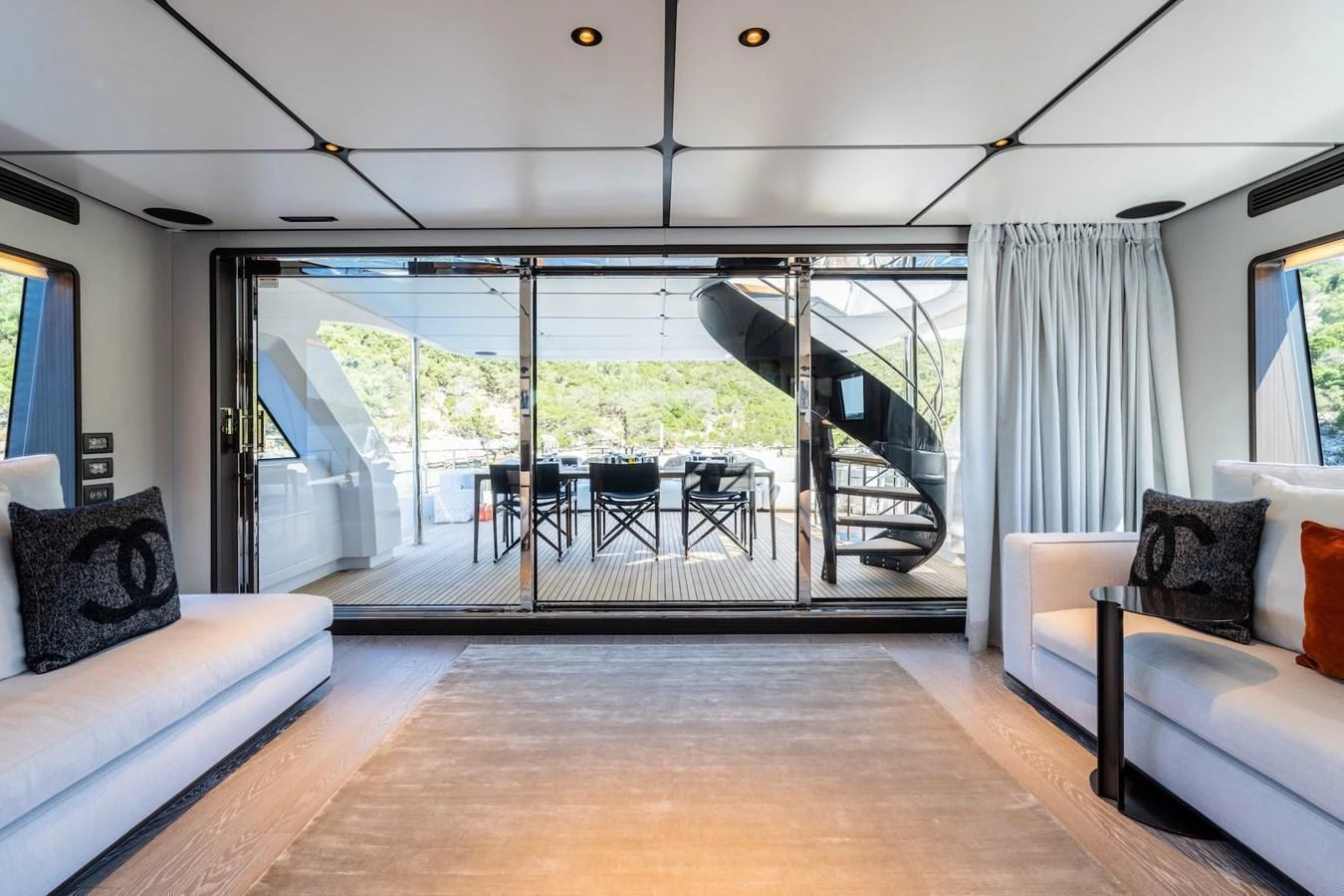 The salon offers a spacious and elegant area with a view of the outdoor deck and spiral staircase. aboard AT ONE Yacht for Sale