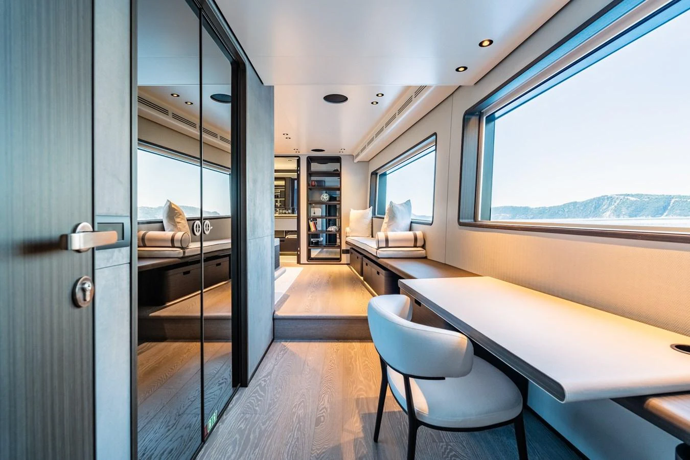 The yacht's interior features a modern, well-lit workspace with large windows offering stunning views. aboard AT ONE Yacht for Sale