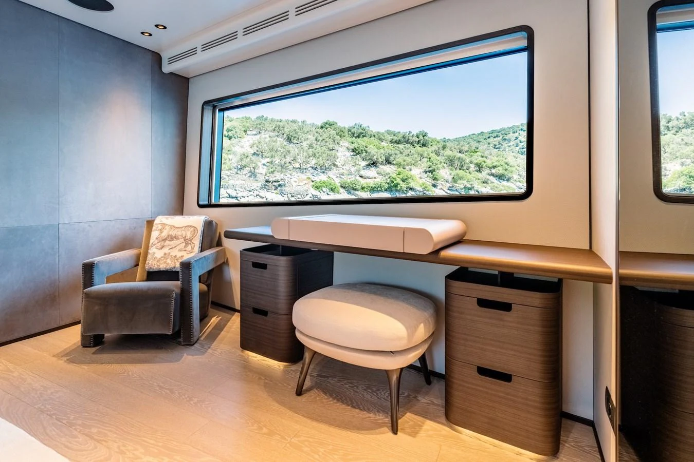 A serene interior space featuring a comfortable chair, a desk, and a large window with a scenic view. aboard AT ONE Yacht for Sale
