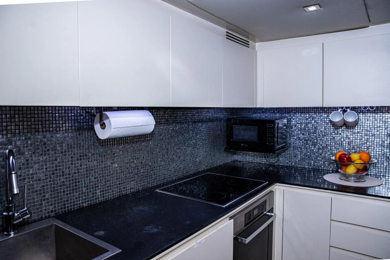The modern galley features sleek cabinetry, a black countertop, and a stylish backsplash. aboard DOROTHY ANN Yacht for Sale