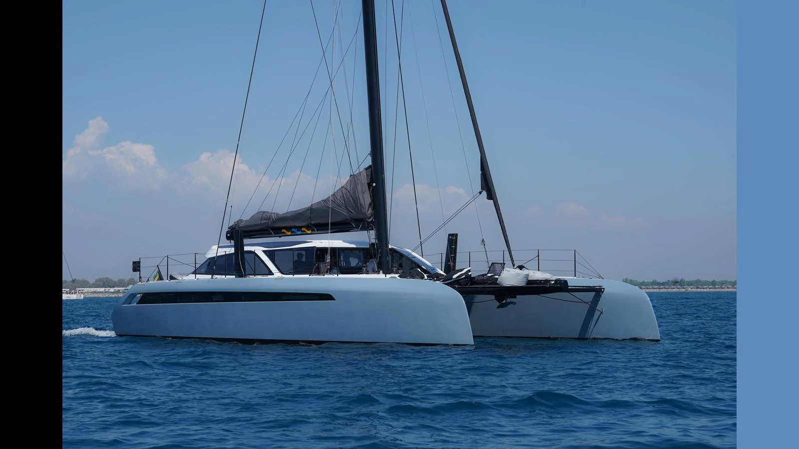 A sleek catamaran glides through calm blue waters under a clear sky. aboard GUNBOAT 80 Yacht for Sale