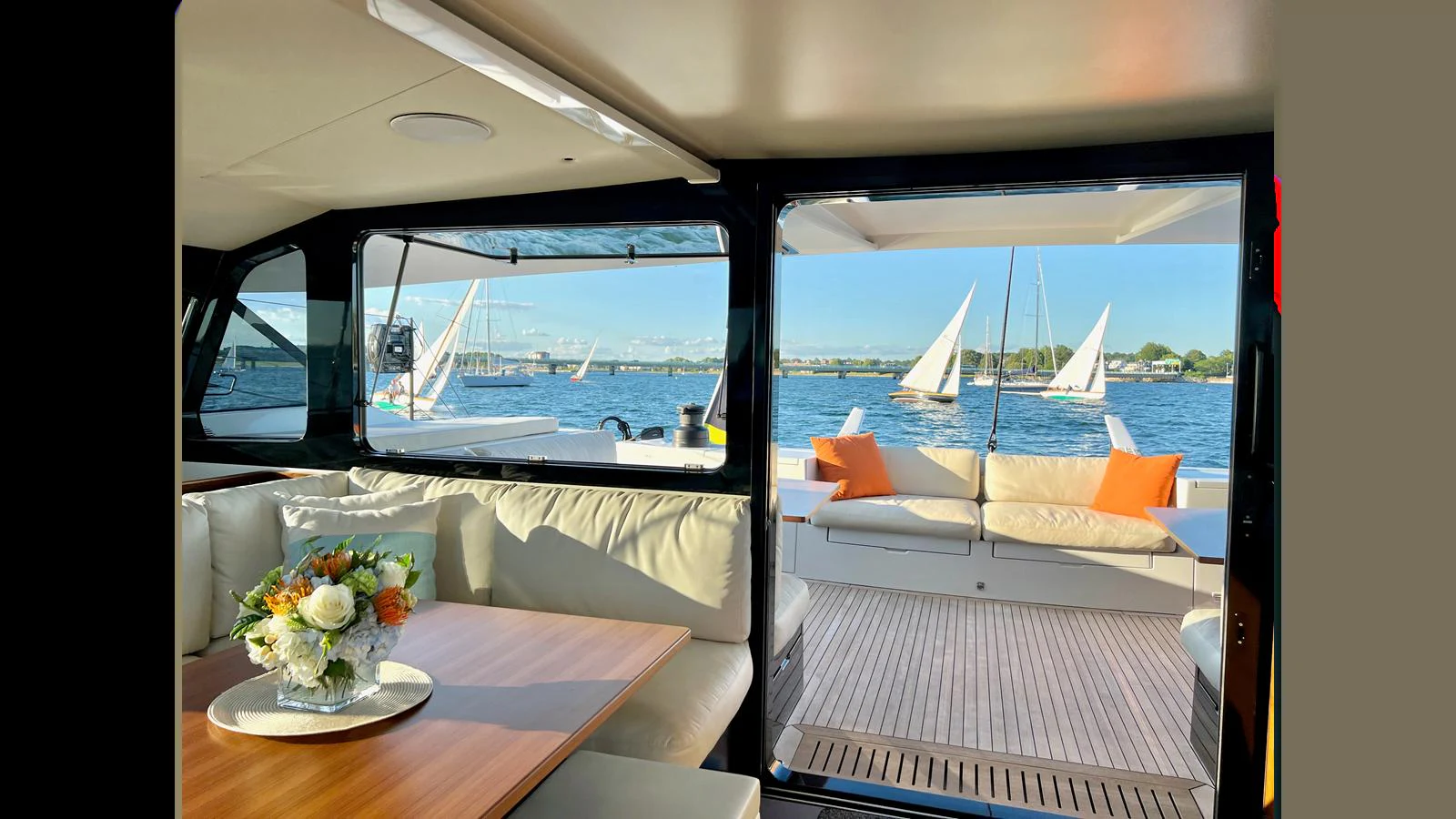 The salon offers a comfortable and stylish space with a view of the water and sailboats outside. aboard GUNBOAT 80 Yacht for Sale