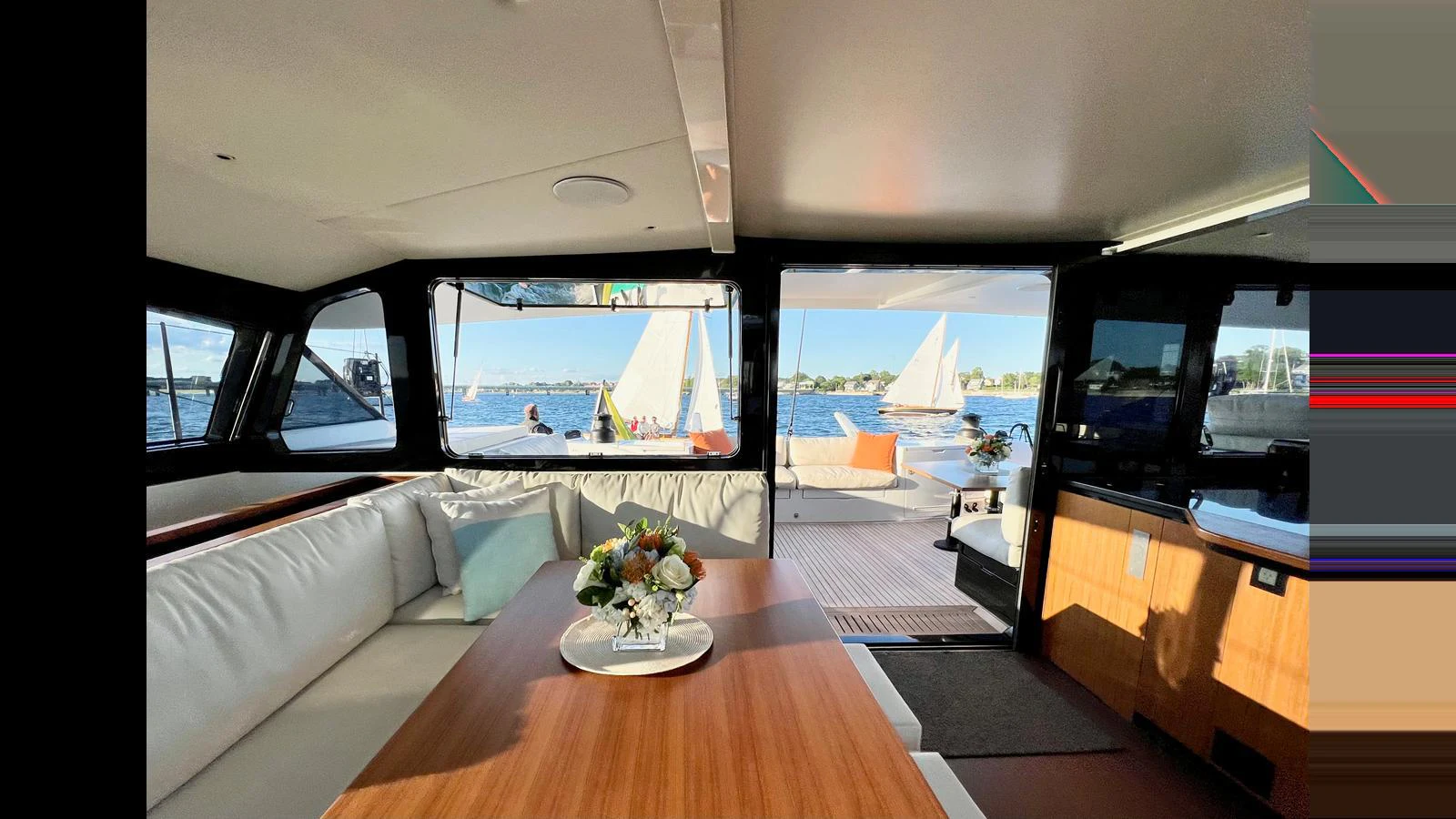 The yacht's salon offers a cozy and inviting space with a view of the water and sailboats outside. aboard GUNBOAT 80 Yacht for Sale