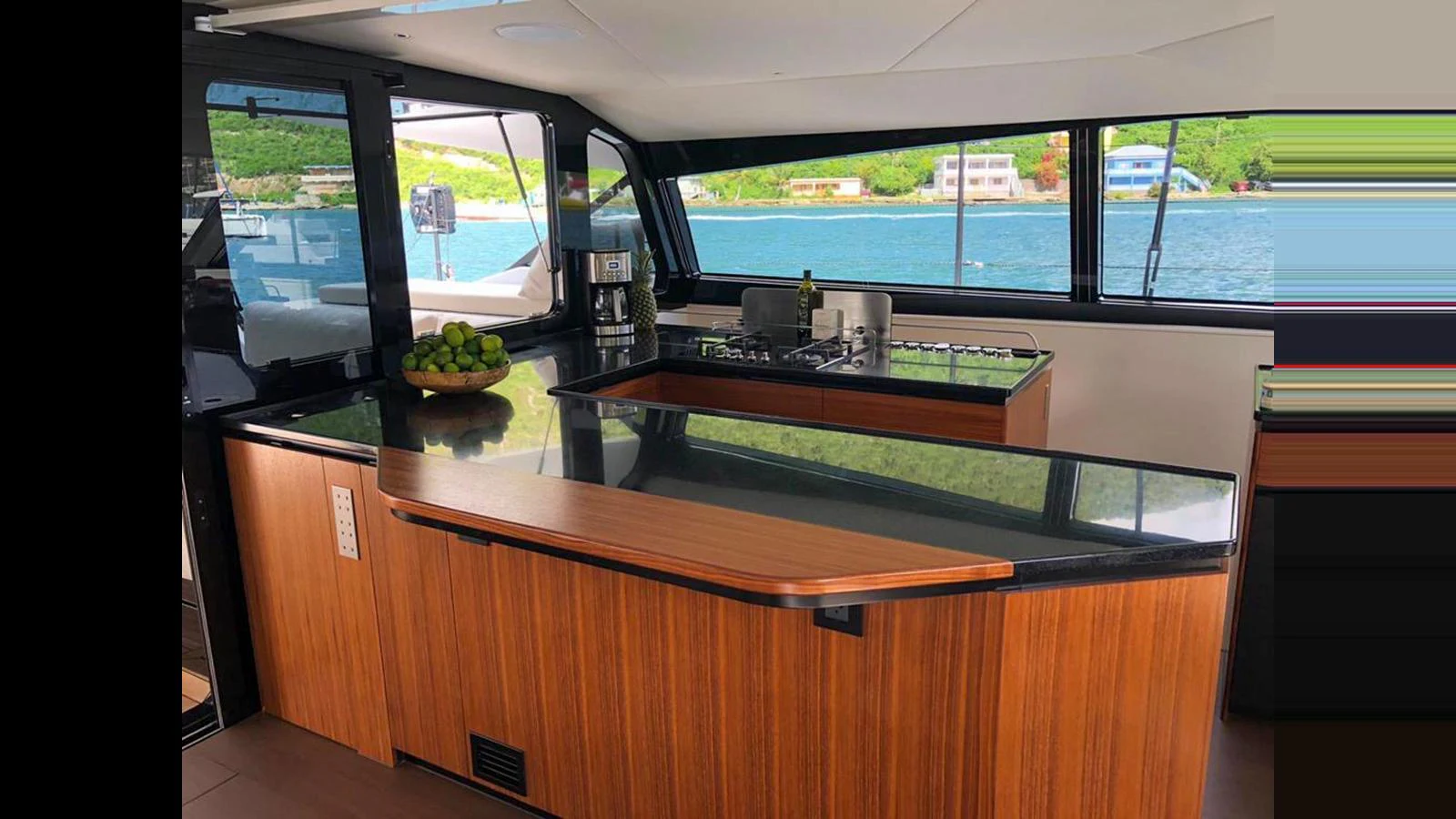 The yacht's galley features sleek wooden cabinetry and modern appliances, with a scenic view through large windows. aboard GUNBOAT 80 Yacht for Sale