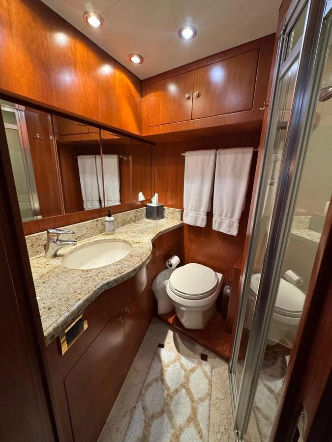 The yacht's bathroom features elegant wood cabinetry, a granite countertop, and a glass-enclosed shower. aboard 68' HARGRAVE OPEN BRIDGE Yacht for Sale