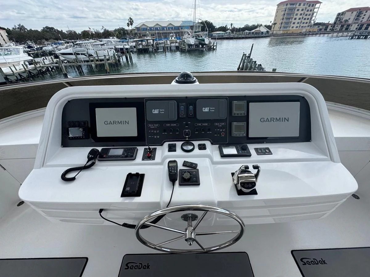 The helm station features advanced navigation equipment and a sleek steering wheel, offering a commanding view of the marina. aboard 68' HARGRAVE OPEN BRIDGE Yacht for Sale