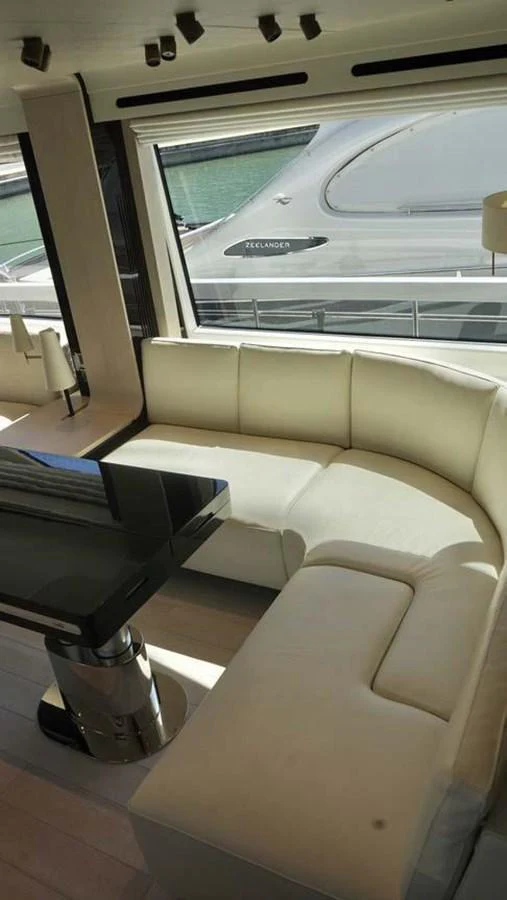 The yacht's salon features a plush, curved seating area with a sleek, modern table, bathed in natural light from large windows. aboard KOKO Yacht for Sale