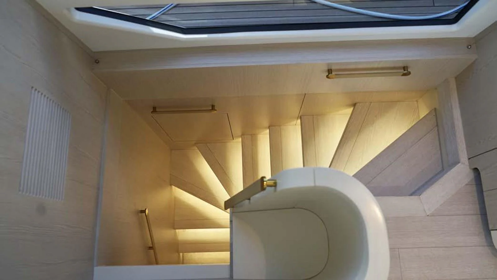 A beautifully illuminated staircase with elegant wooden steps and brass handrails. aboard KOKO Yacht for Sale