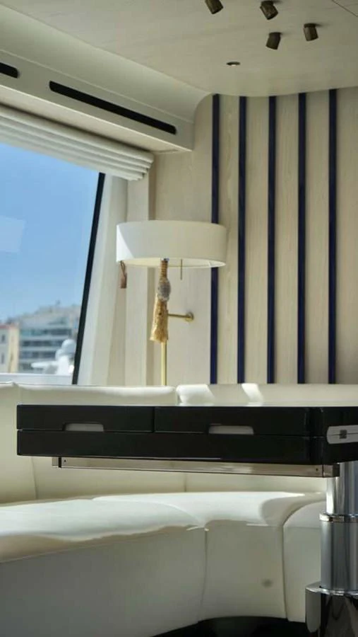 The yacht's interior features a stylish seating area with a modern table and a window offering a view of the outside. aboard KOKO Yacht for Sale