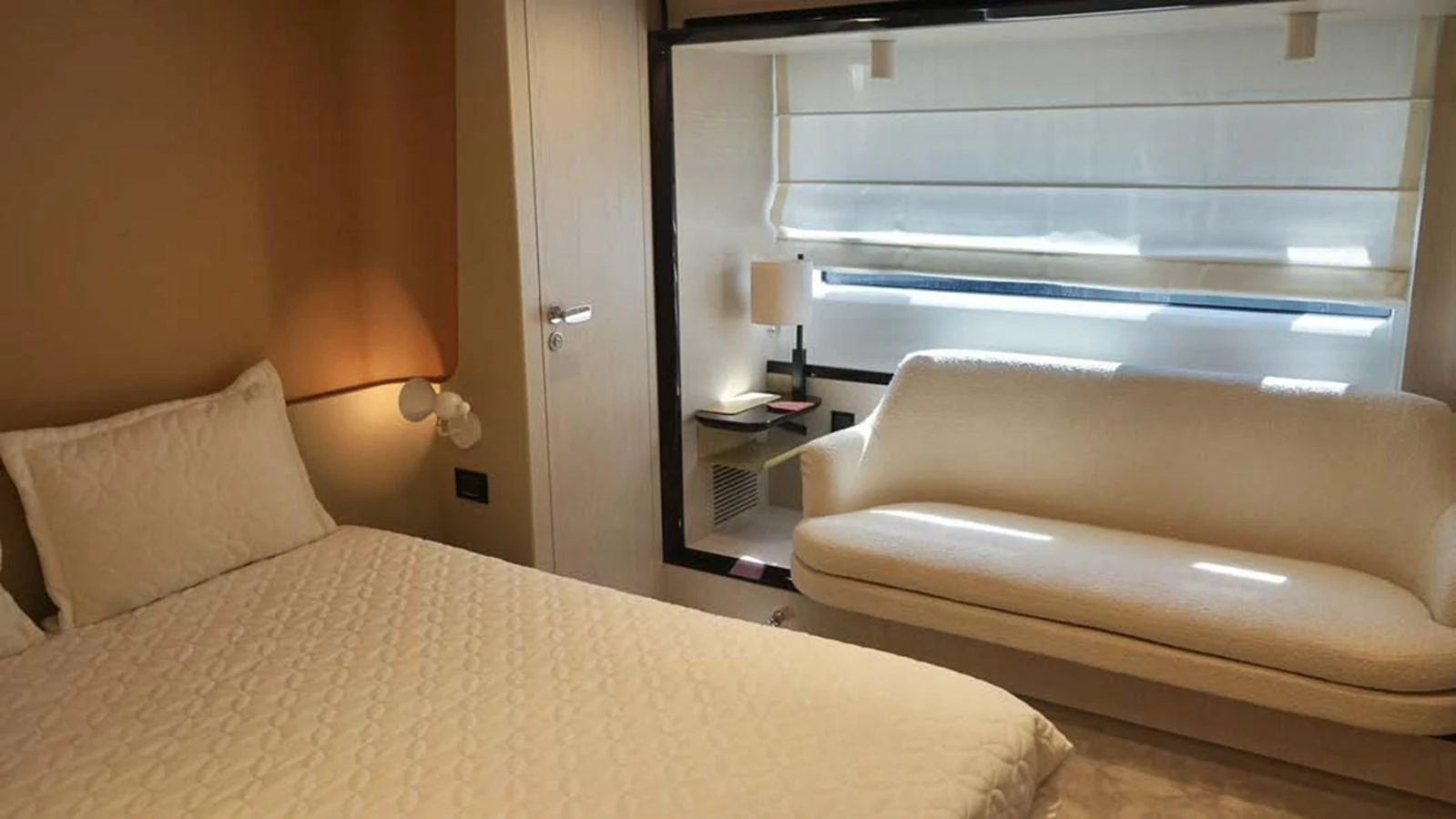 A cozy stateroom featuring a comfortable bed and a stylish sofa by the window. aboard KOKO Yacht for Sale