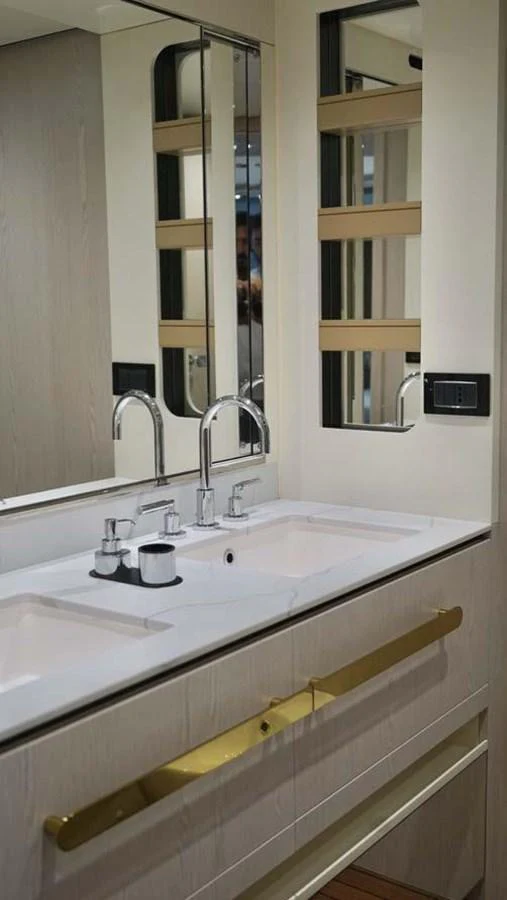 The yacht's bathroom features a sleek double sink with modern fixtures and ample mirror space. aboard KOKO Yacht for Sale