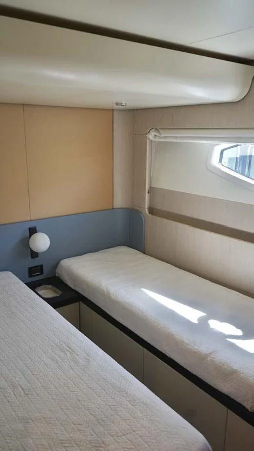 The guest cabin features cozy single beds with a modern, minimalist design. aboard KOKO Yacht for Sale