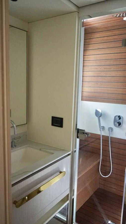The yacht's bathroom features a modern sink and a wooden-accented shower area. aboard KOKO Yacht for Sale