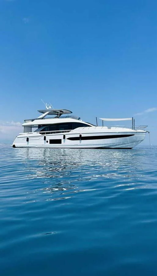 A sleek, modern yacht glides gracefully on calm blue waters under a clear sky. aboard KOKO Yacht for Sale