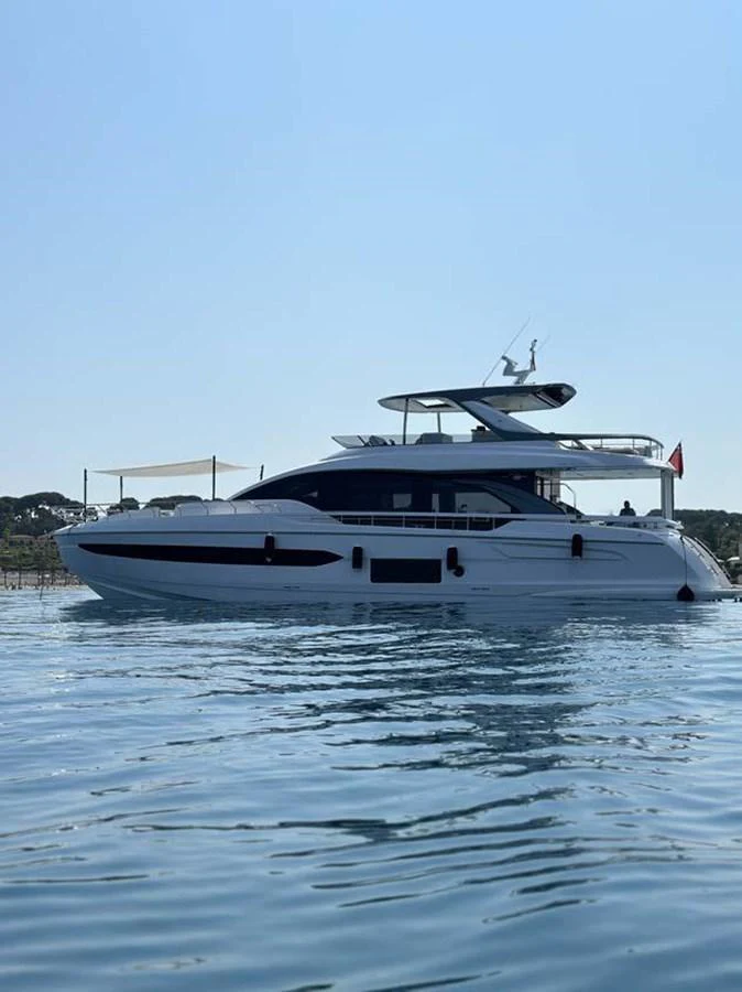 A sleek and modern yacht is anchored on calm waters under a clear blue sky. aboard KOKO Yacht for Sale