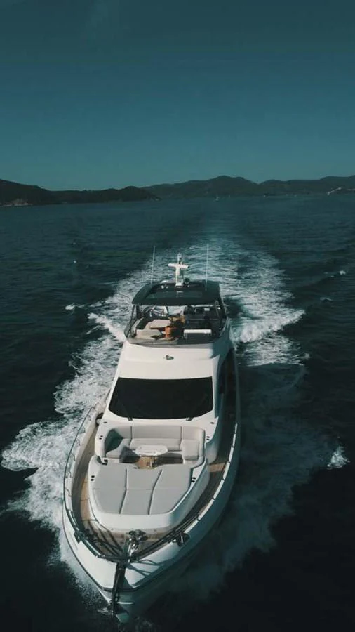 A sleek yacht cruises through calm waters, leaving a trail of white wake behind. aboard KOKO Yacht for Sale