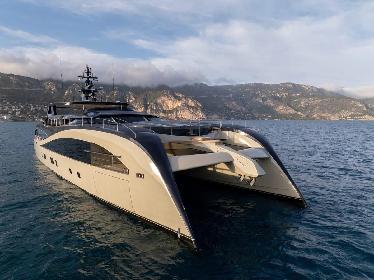 A sleek and modern yacht glides gracefully on the water against a backdrop of scenic coastal mountains. aboard SEAWOLF X Yacht for Sale