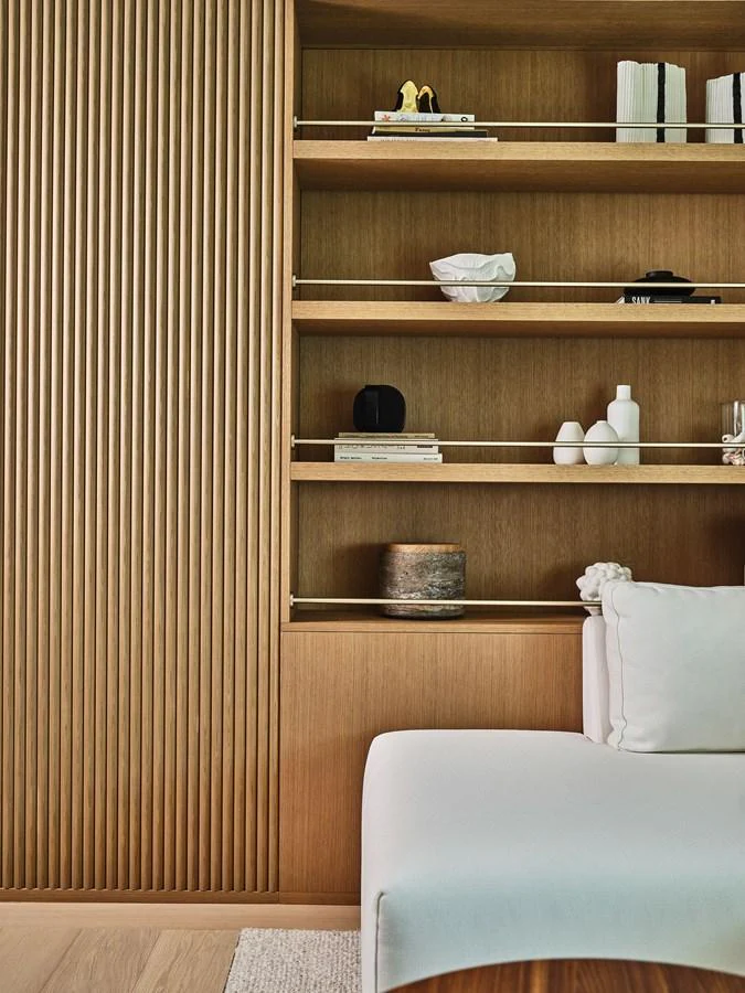 The yacht's interior features a stylish wooden bookshelf with elegant decor items and a plush white chair. aboard SEAWOLF X Yacht for Sale
