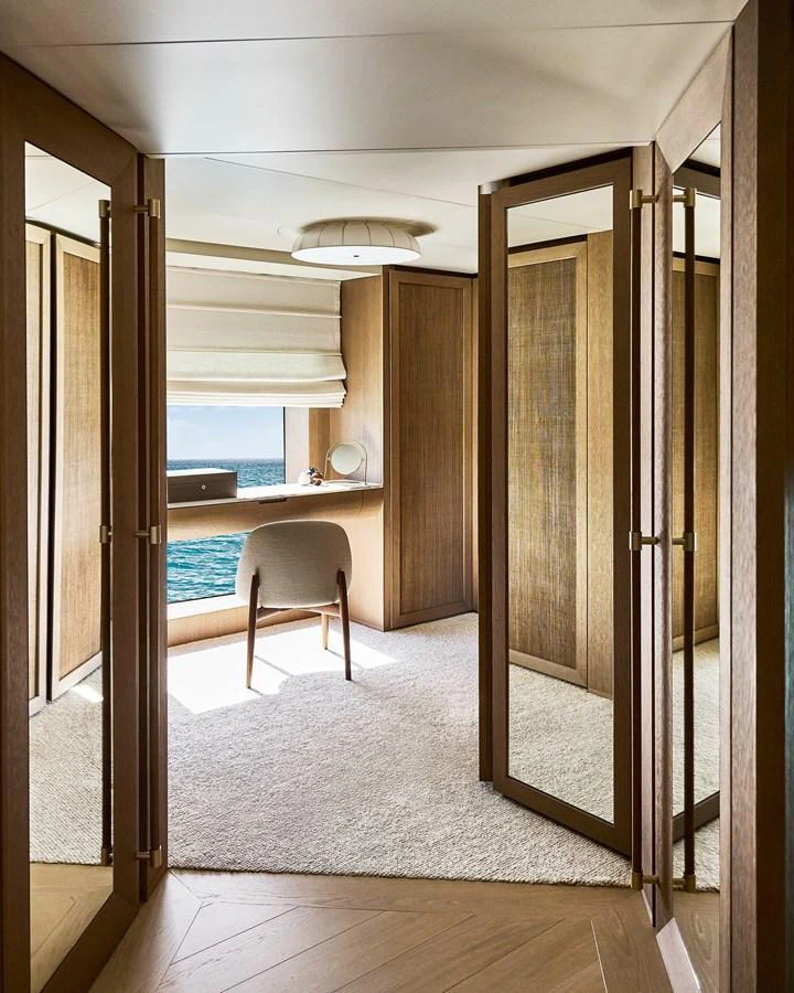 A serene vanity area with a chair and mirror, featuring elegant wood paneling and a view of the sea. aboard SEAWOLF X Yacht for Sale