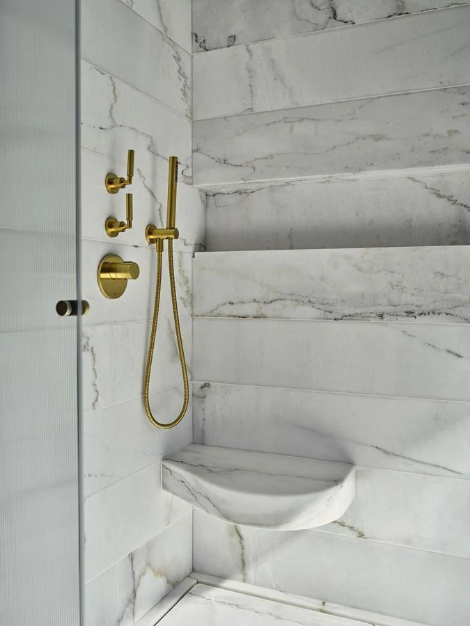 The yacht's bathroom features elegant marble walls and a luxurious gold shower fixture. aboard SEAWOLF X Yacht for Sale