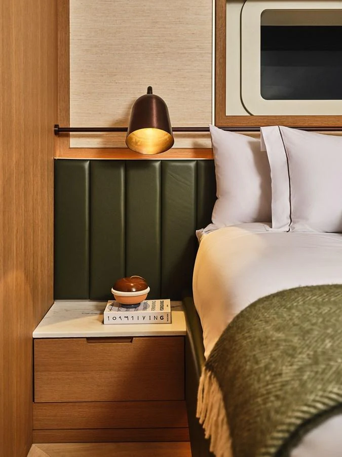 A cozy stateroom featuring a plush bed, elegant lighting, and a bedside table with a book and decorative item. aboard SEAWOLF X Yacht for Sale