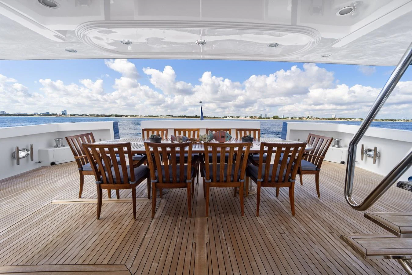a wooden table and chairs on a deck overlooking a large body of water aboard STAMPEDE Yacht for Sale