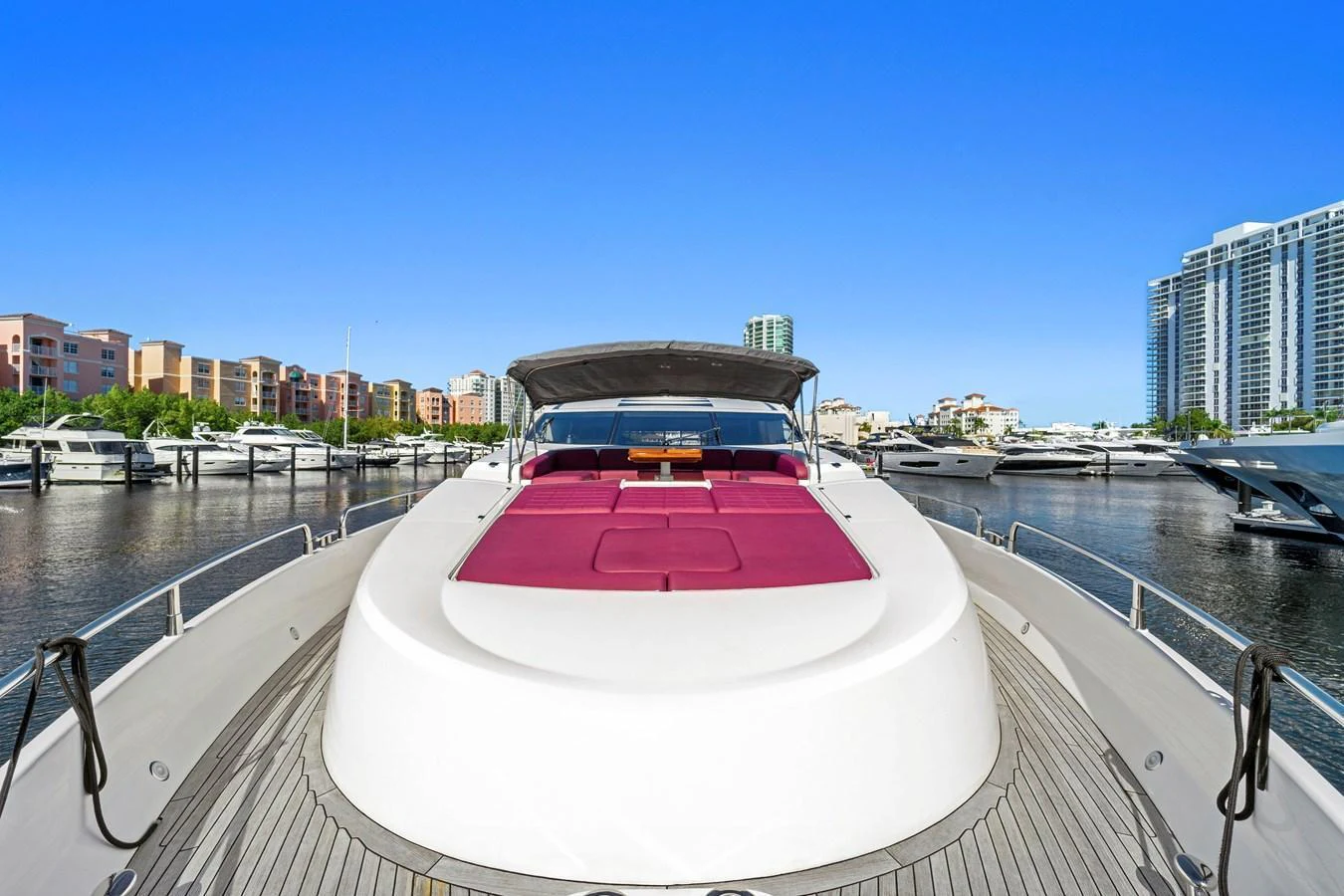 The yacht's bow area features a spacious sunpad with vibrant red cushions, perfect for relaxation while docked in a marina. aboard GBXSK84PRD13 Yacht for Sale
