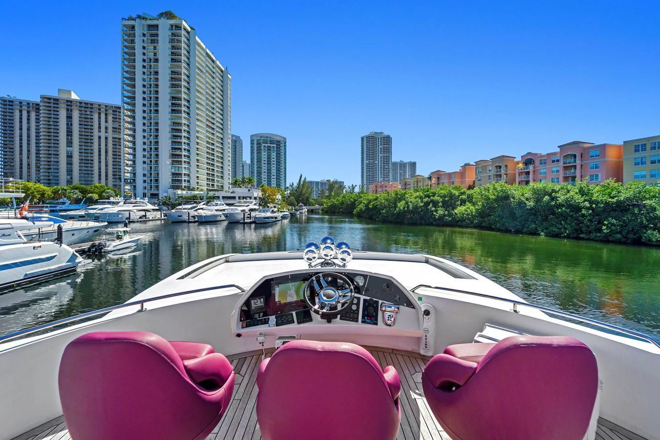 The helm offers a commanding view of the marina, framed by luxurious red seating and modern controls. aboard GBXSK84PRD13 Yacht for Sale