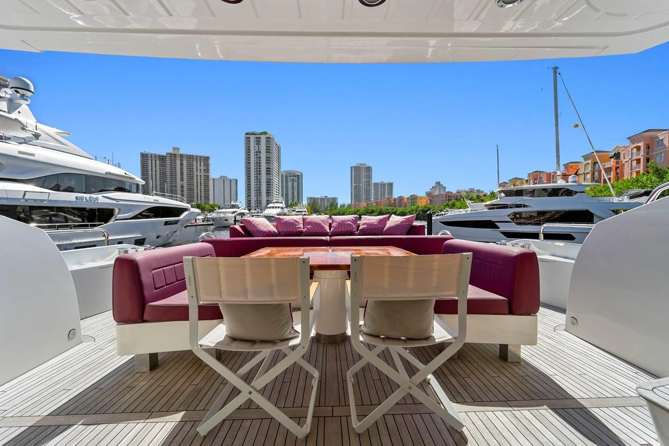 The aft deck features a spacious seating area with vibrant cushions and a dining table, perfect for alfresco dining with a view of the marina. aboard GBXSK84PRD13 Yacht for Sale