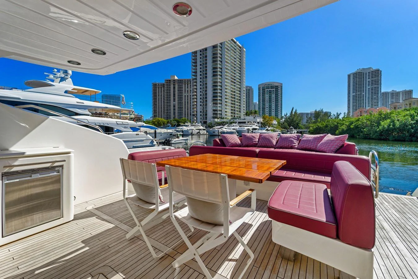 The aft deck features a comfortable seating area with a dining table, perfect for enjoying meals with a view of the marina. aboard GBXSK84PRD13 Yacht for Sale