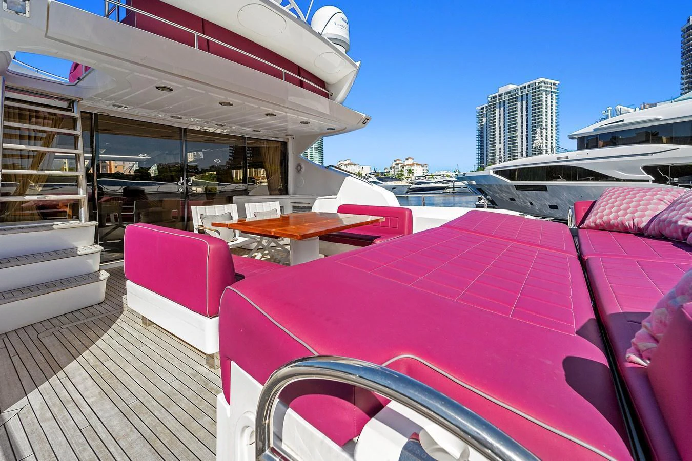 The aft deck features vibrant pink seating and a dining area, perfect for outdoor relaxation and entertainment. aboard GBXSK84PRD13 Yacht for Sale