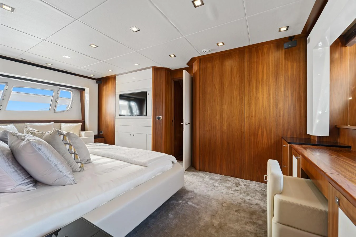 The master stateroom features luxurious wood paneling, a plush bed, and ample natural light. aboard GBXSK84PRD13 Yacht for Sale