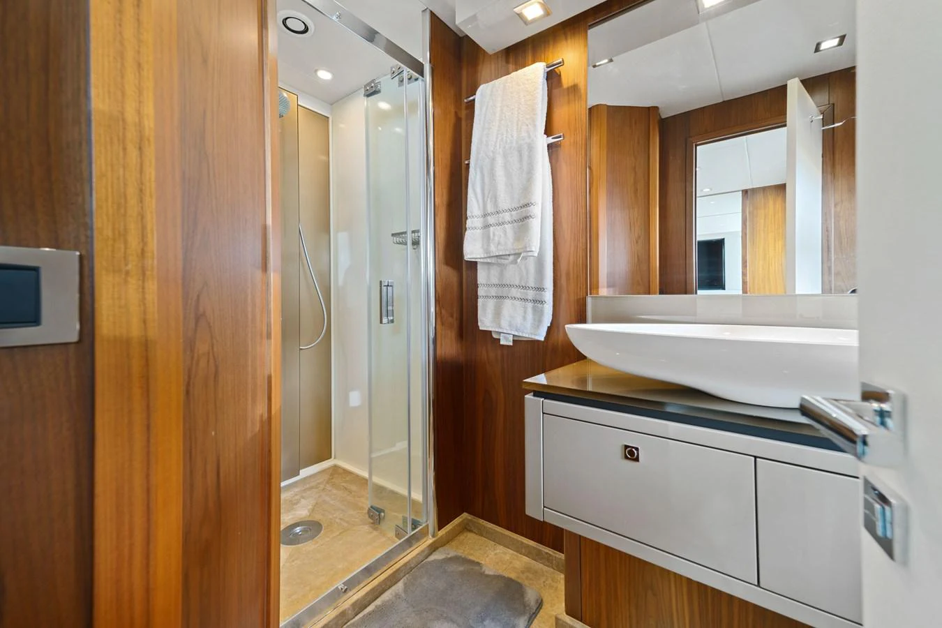 A sleek and modern yacht bathroom with wooden accents and a glass-enclosed shower. aboard GBXSK84PRD13 Yacht for Sale