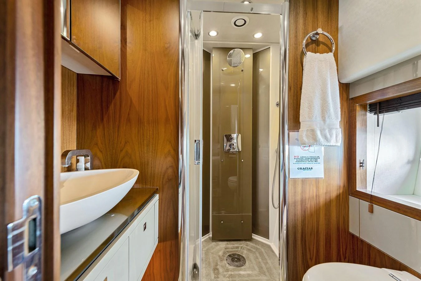 The yacht's bathroom features a modern shower, sleek sink, and warm wood accents. aboard GBXSK84PRD13 Yacht for Sale