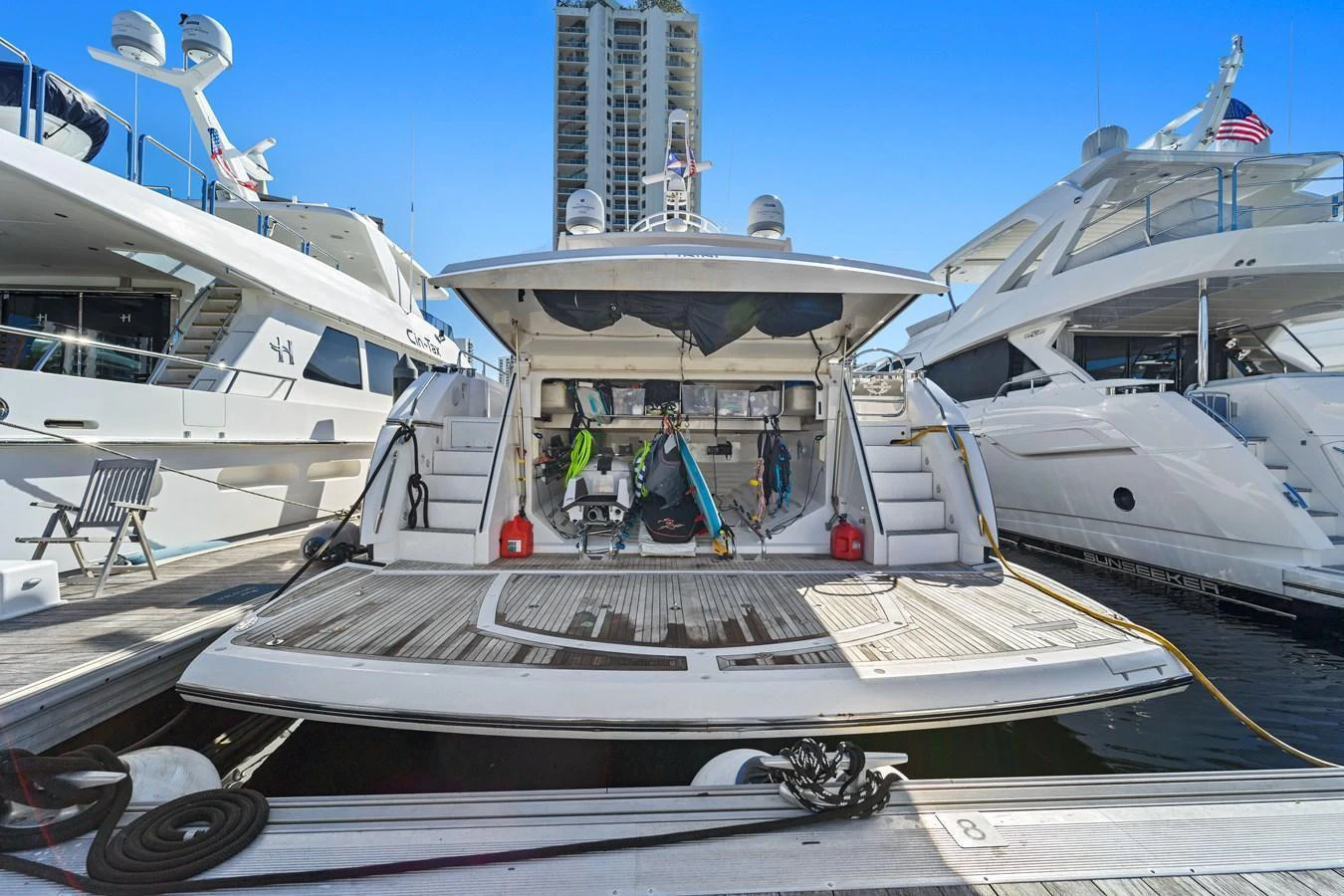 The yacht's aft deck is shown docked at a marina, featuring a spacious swim platform and open storage area. aboard GBXSK84PRD13 Yacht for Sale