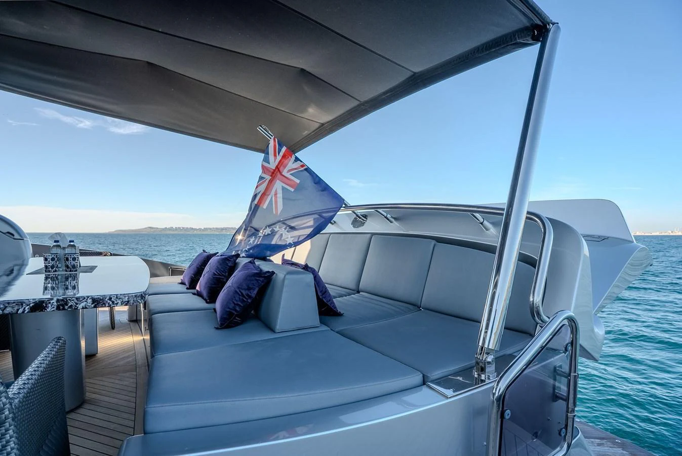 The aft deck features a spacious lounging area with plush seating and a dining table, perfect for relaxation and entertaining. aboard SPECTRE Yacht for Sale