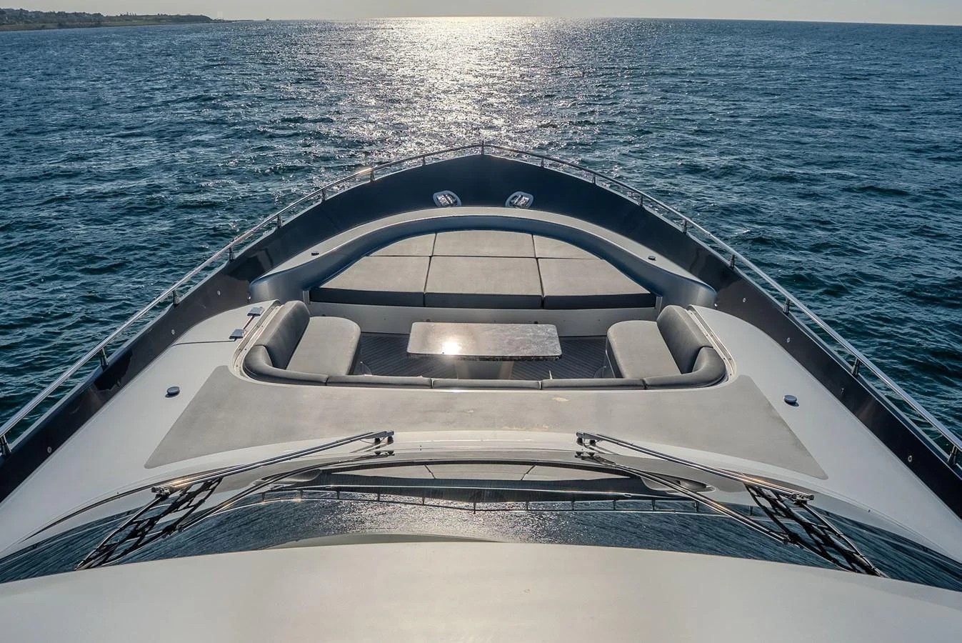 The yacht's bow features a spacious sunbathing area with plush seating and a central table, perfect for relaxation. aboard SPECTRE Yacht for Sale