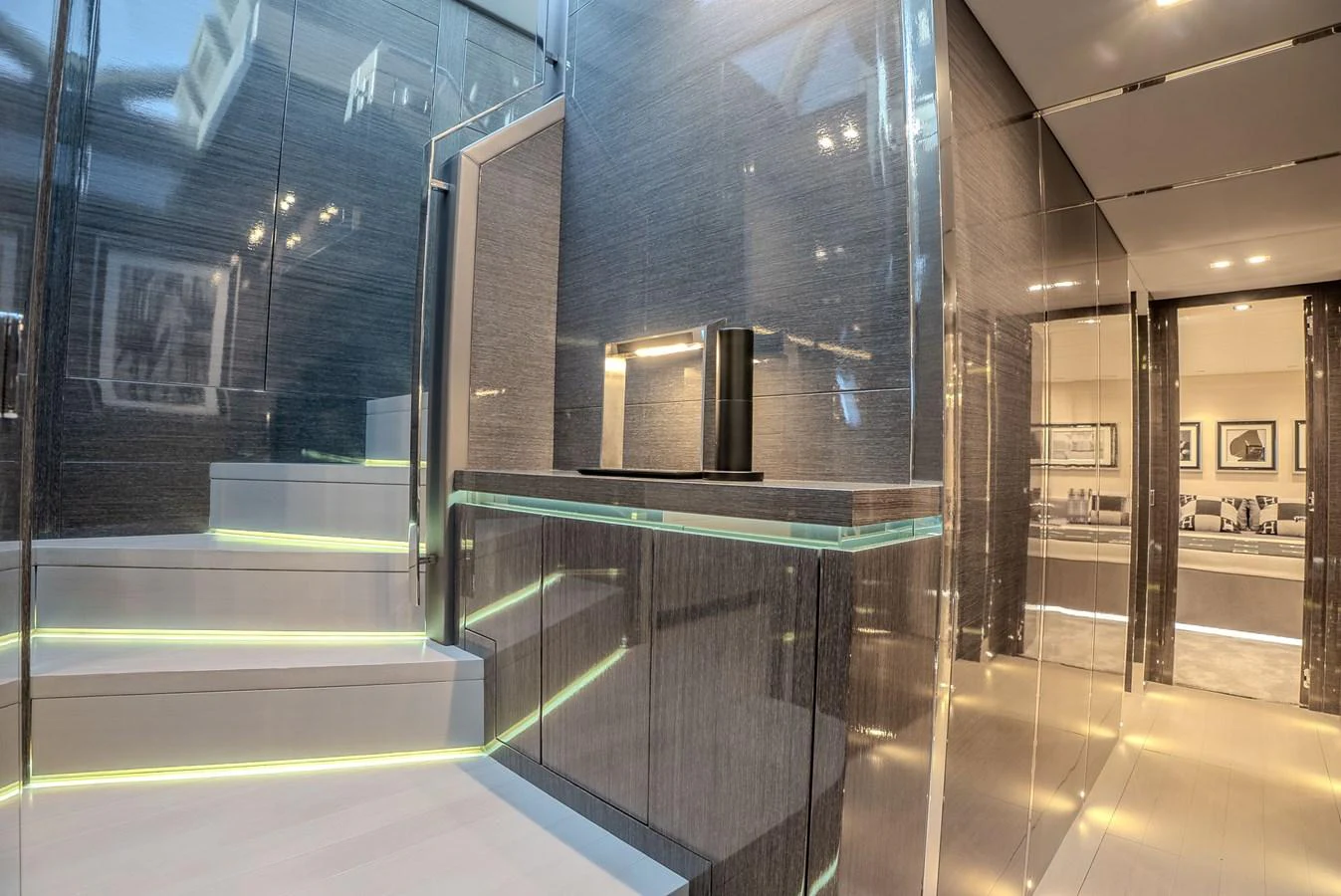 The yacht's interior features a modern staircase with sleek, reflective surfaces and ambient lighting. aboard SPECTRE Yacht for Sale