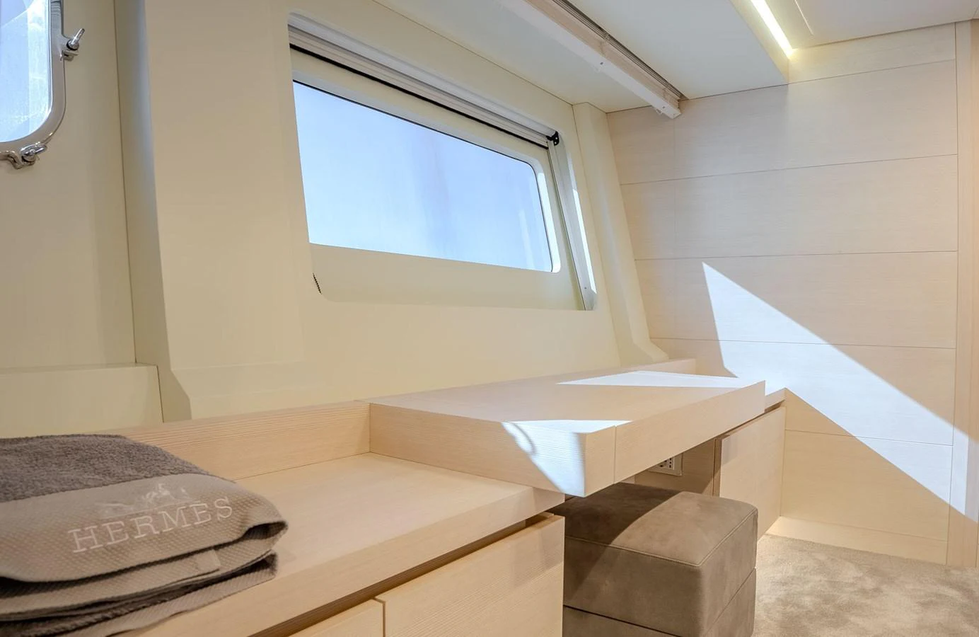 A serene and well-lit interior space with a window and a neatly arranged desk area. aboard SPECTRE Yacht for Sale